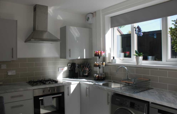 Completed white fitted kitchen with oven extractor hood sink and washing machine