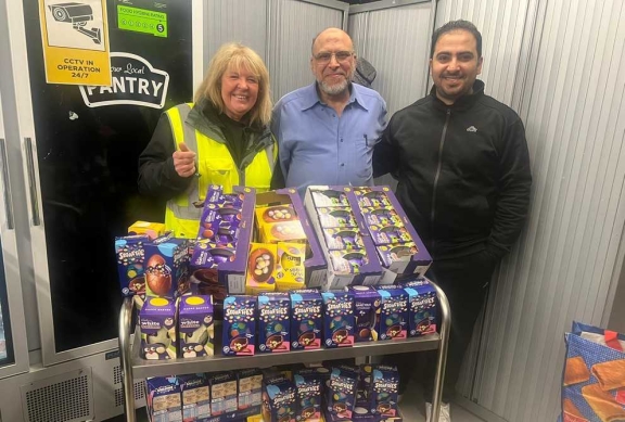Three people standing behind a trolley filled with donated chocolate easter eggs