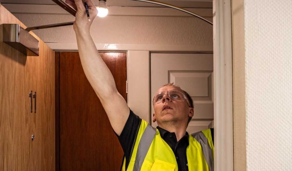 A Connolly tradesperson adjusting a door closer in a communal corridor