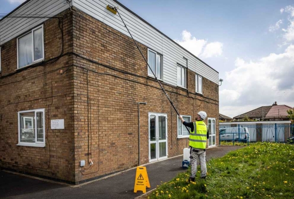 A connolly worker carrying out exterior maintenance on a brick apartment building