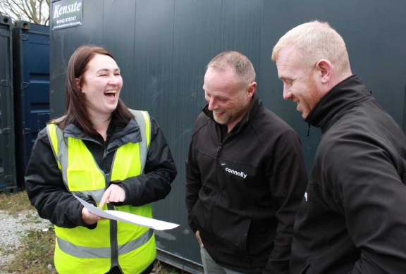 Three Connolly colleagues smiling together beside site storage units